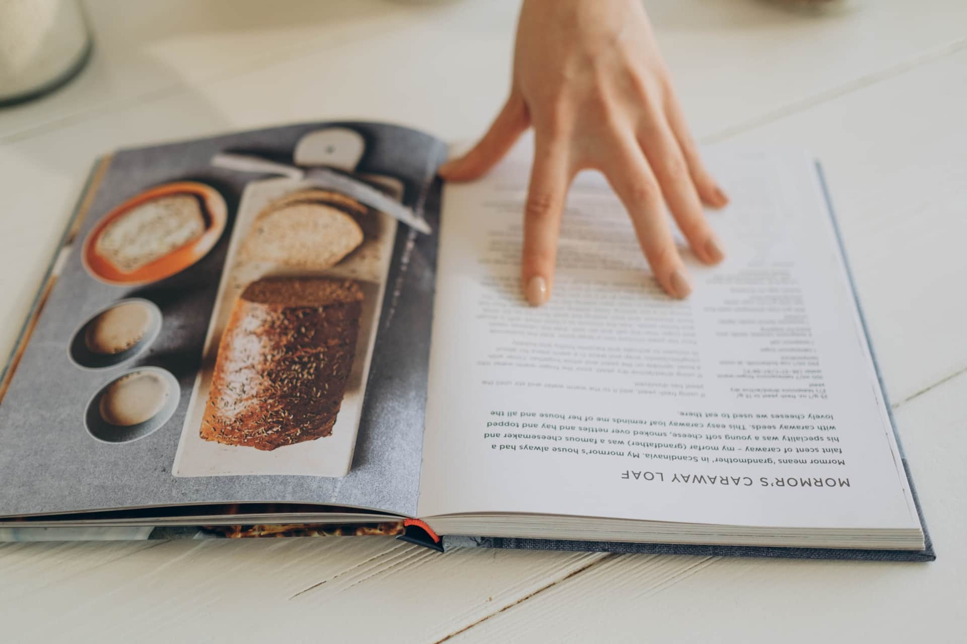 A hand resting on an open cookbook