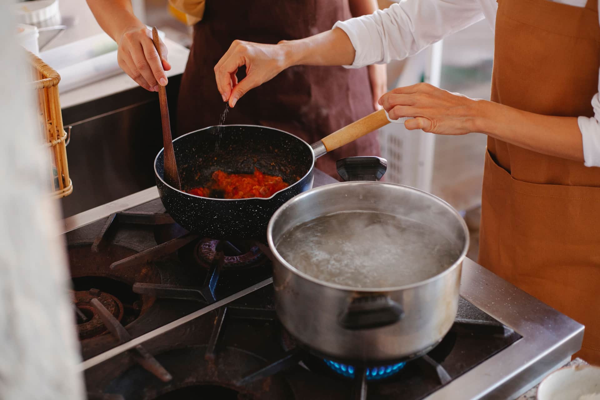 Hands stirring a pot on a stove
