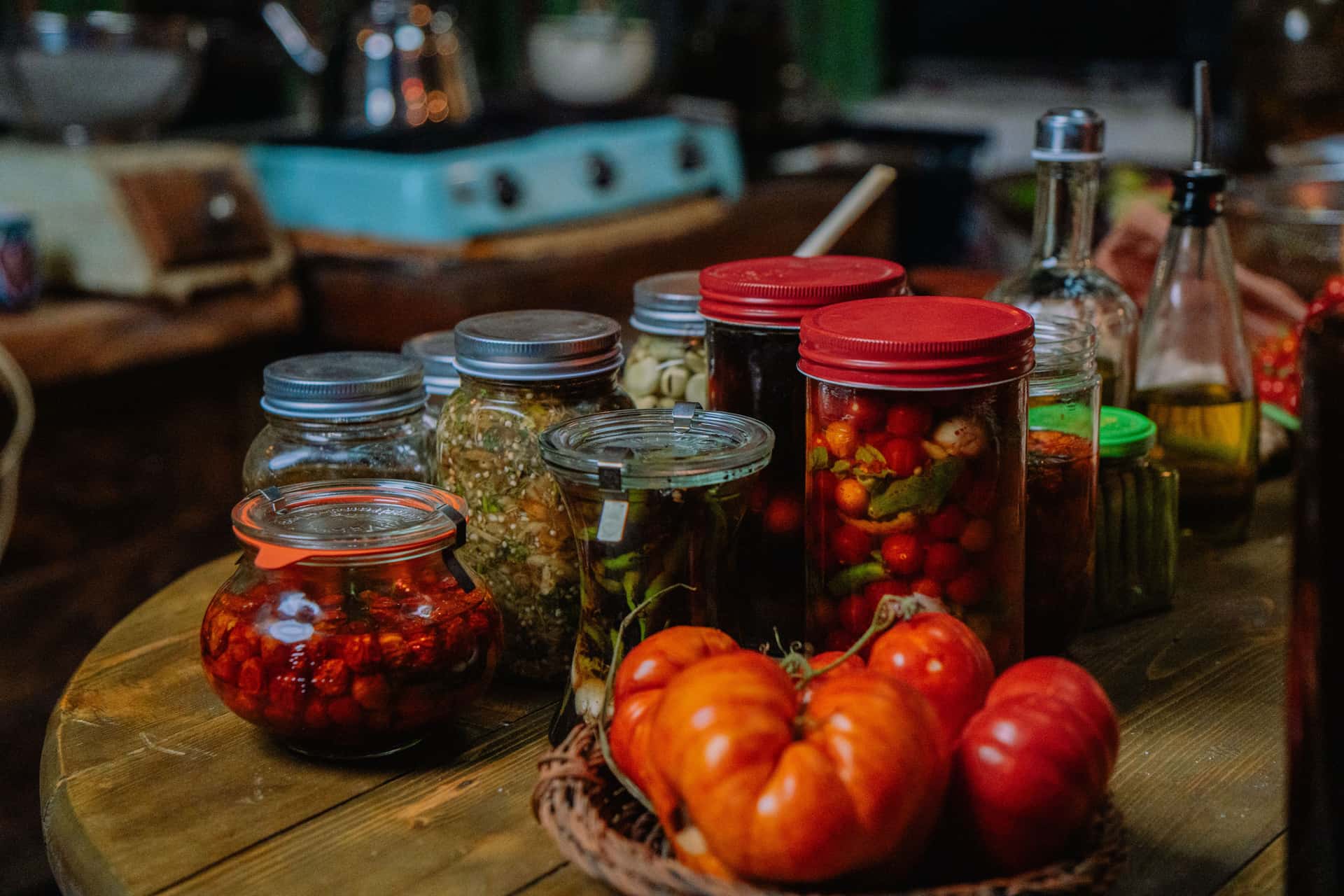 Home-preserved vegetables in glass jars on a dark wooden shelf
